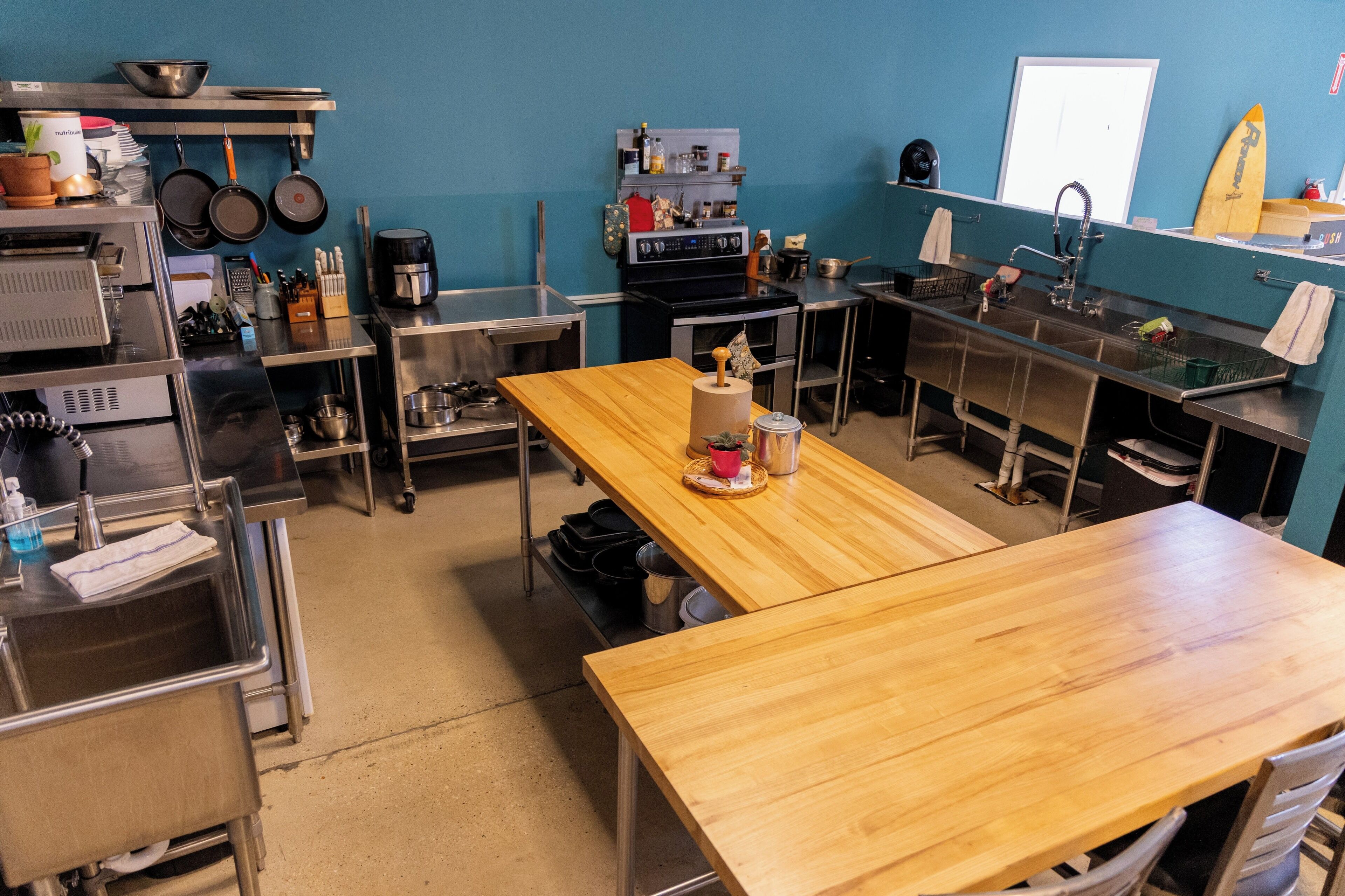 Una cocina con electrodomésticos de acero inoxidable, una mesa de madera y una pared azul.