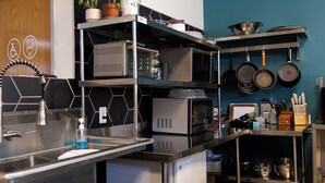 A modern kitchen with stainless steel appliances, a microwave, and a variety of pots and pans. - Hostel SoHa (South Haven)