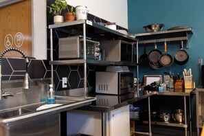 A modern kitchen with stainless steel appliances, a microwave, and a variety of pots and pans. - Hostel SoHa (South Haven)