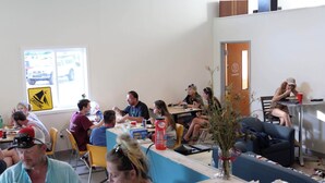 A communal dining area with tables, chairs, and a window with a view of the street. - Hostel SoHa (South Haven)