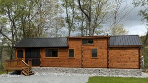 A wooden cabin with a porch, a stone foundation, and a gravel driveway. - Tiny Cabin #3 by Windham NY Escape 'Forest View' (Hensonville)