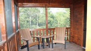 A wooden deck with a table and four chairs, overlooking a forested area. - Tiny Cabin #3 by Windham NY Escape 'Forest View' (Hensonville)