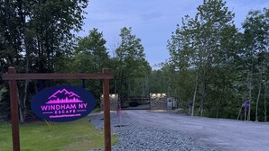 A gravel path leading to a gate with a sign for Windham NY Escape. - Tiny Cabin #3 by Windham NY Escape 'Forest View' (Hensonville)