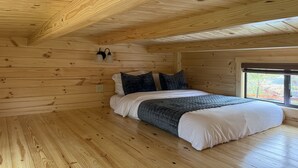 A wooden cabin bedroom with a bed, two wall-mounted lights, and a window. - Tiny Cabin #5 by Windham NY Escape 'Scenic Stay' (Hensonville)