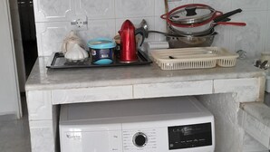 A compact kitchen with a microwave, a washing machine, and various kitchen utensils on the countertop. - 10 m walk from the sea, lovely apartment for rent, ideal for families (Annaba)
