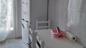 A kitchen with white cabinets, a white table, and a white chair. - 10 m walk from the sea, lovely apartment for rent, ideal for families (Annaba)