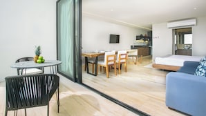 A modern hotel room with a dining area, a sofa, and a TV.
