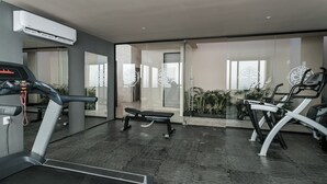 A modern gym with treadmills, a bench, and exercise bikes.