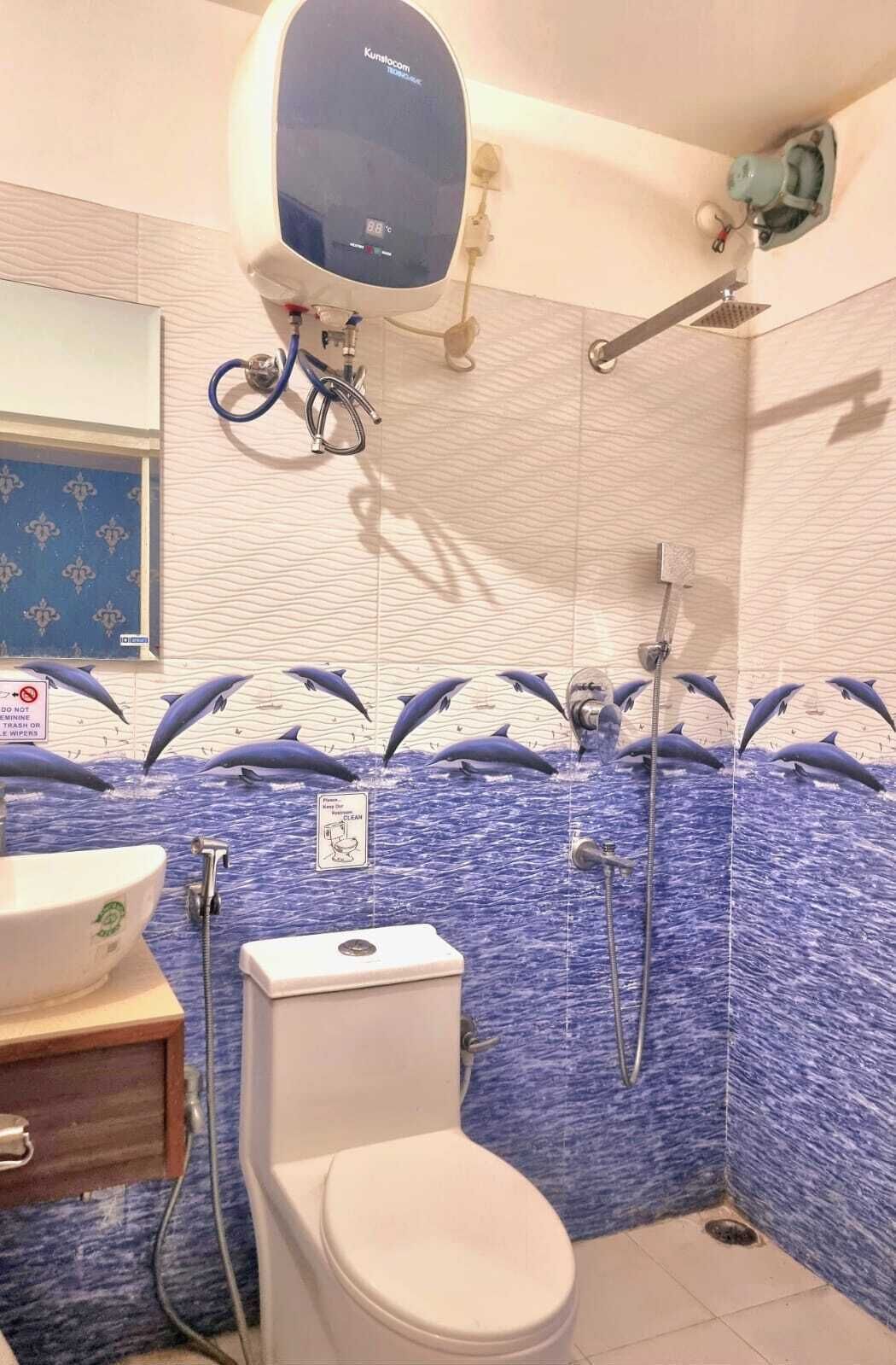 Um banheiro com parede azulejada em azul, vaso sanitário, pia e chuveiro.