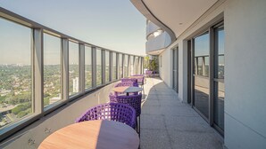 A high-rise balcony with purple wicker furniture and a view of the city. - Sunset Rooftop Studio - Comfort & Modernity in Brooklyn (Jardim das Acacias São Paulo)