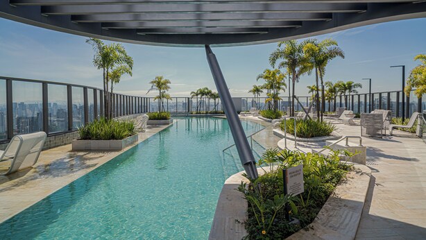 A rooftop infinity pool with clear blue water, surrounded by lounge chairs and potted plants, overlooking a city skyline. - Sunset Rooftop Studio - Comfort & Modernity in Brooklyn (Jardim das Acacias São Paulo)