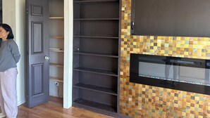 Una habitación con una puerta de madera oscura, salpicadero de azulejos y microondas empotrado.