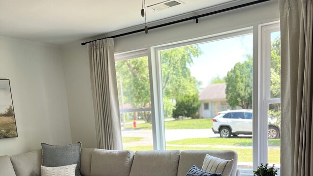 Una sala de estar con un sofá modular, una mesita redonda y un ventanal con cortinas.