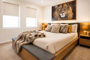 A bedroom with a bed, bedside tables, a bench, a large painting, and a window.