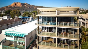 A modern multi-story building with balconies, large windows, and a view of a mountain. - Beachfront Bliss in Townsville on The Strand 3BR Pool and Parking (North Ward)