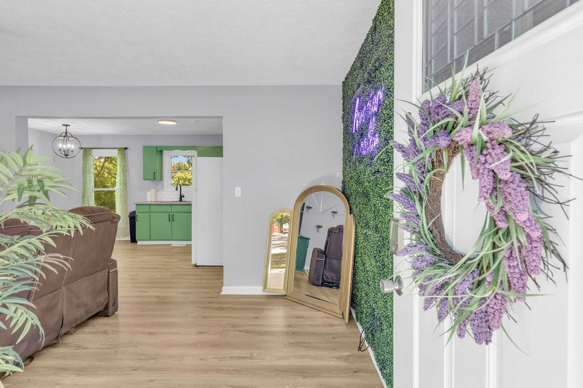 A modern living room with a wooden floor, a green sofa, a mirror, and a wall-mounted mirror.