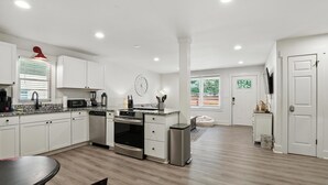 Una cocina moderna con armarios blancos, un horno de acero inoxidable y una mesa de comedor.