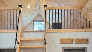 A wooden staircase with a metal railing, a fire extinguisher, and two doors with signs above them.
