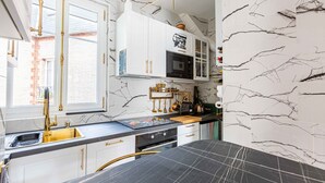 A kitchen with white cabinets, a black countertop, and a marble backsplash.