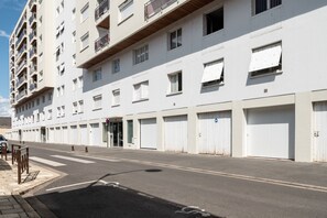 A multi-story building with a row of closed garage doors, a clear sky, and a pedestrian crossing.