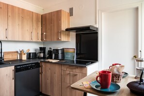 A modern kitchen with wooden cabinets, a black stove, and a coffee maker.