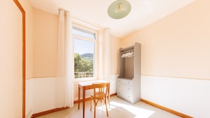 A room with a window, a table, a chair, a wardrobe, and a ceiling light. - Source Fenestre - Proche Puy de Sancy (La Bourboule)