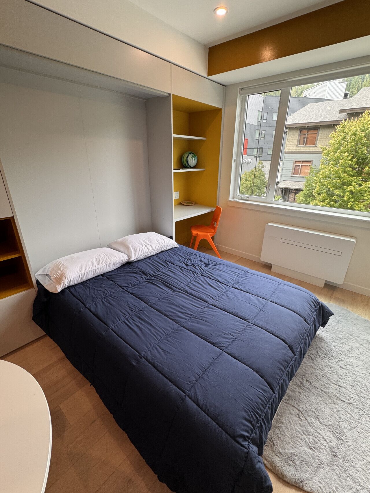 Een slaapkamer met een bed, een bureau en een raam.