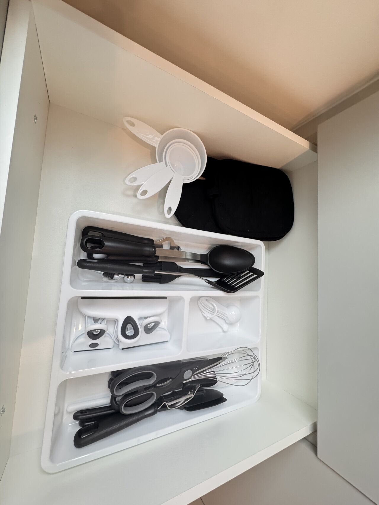 A kitchen drawer with utensils and measuring tools.