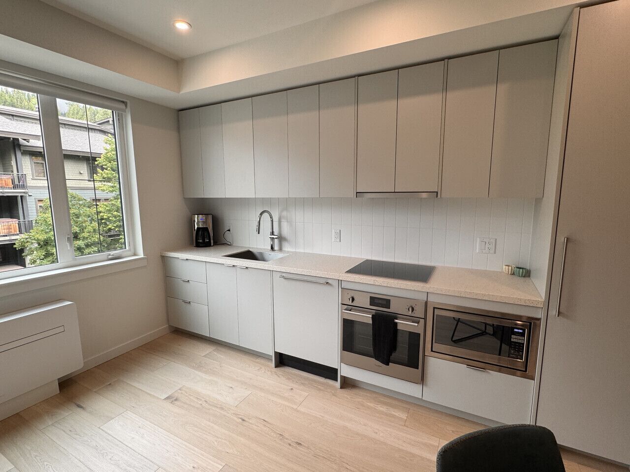A modern kitchen with white cabinets, a sink, a stove, and a microwave.