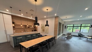 Een moderne keuken met een centraal eiland, hangende verlichting en een eethoek met een lange tafel en stoelen.