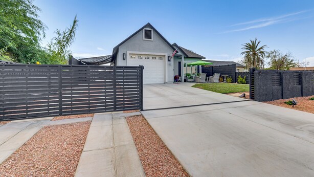 Ein modernes, zweistöckiges Haus mit Garage, Auffahrt und schwarzem Zaun.