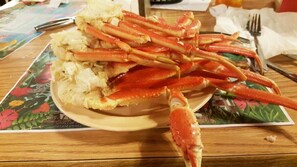 A table with a plate of crab legs and a floral placemat.