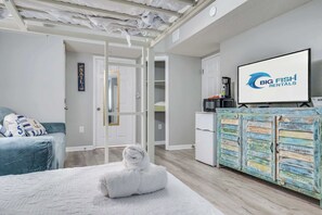 Ein Hotelzimmer mit Bett, einem weißen Handtuch, einem Fernseher und einer Küchenzeile.