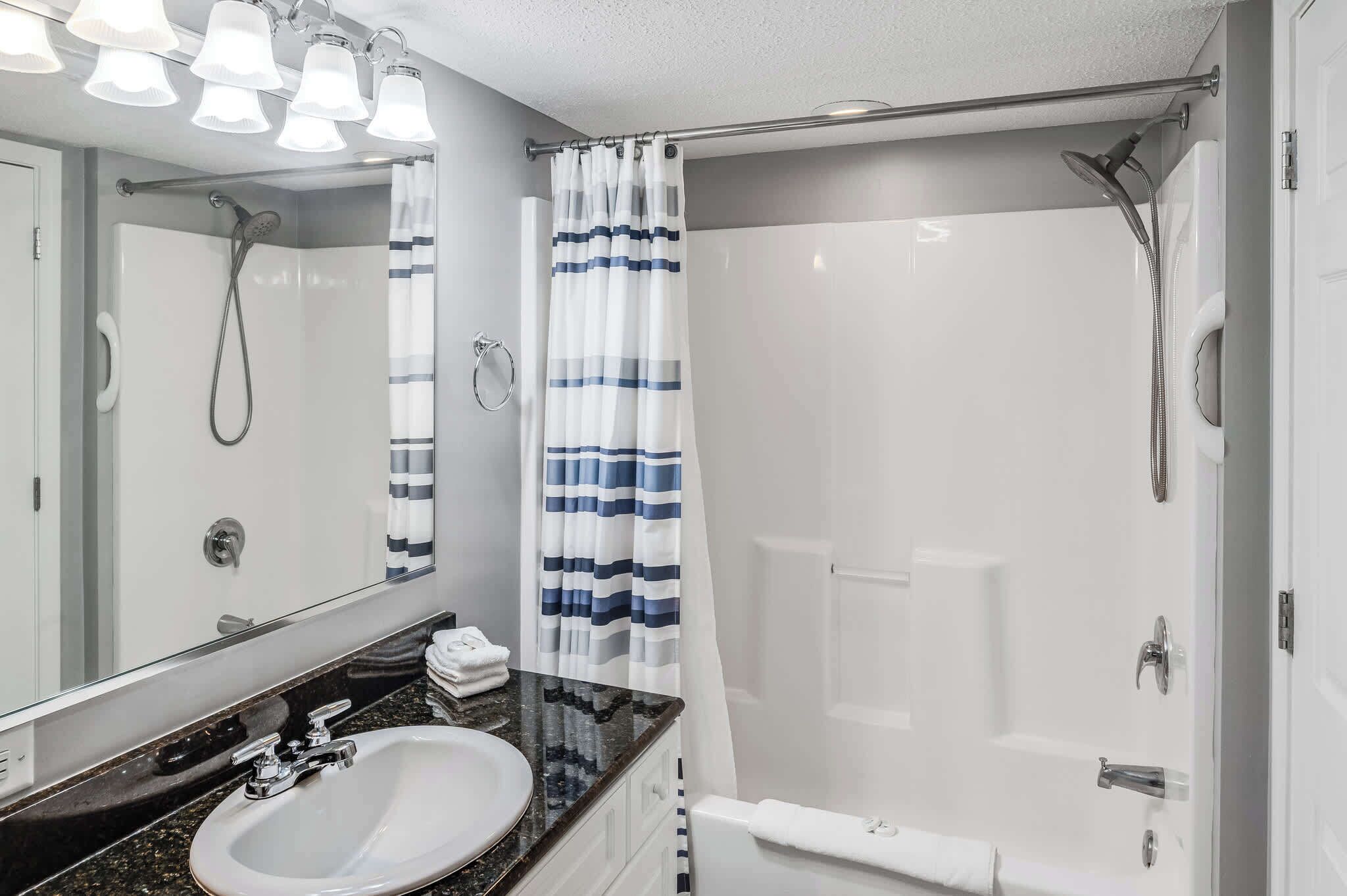 A modern bathroom with a white sink, a mirror, and a shower with a white curtain.