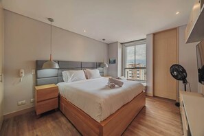 Ein modernes Schlafzimmer mit einem großen Bett, Nachttischen, einem Deckenventilator und einem Fenster mit Blick.