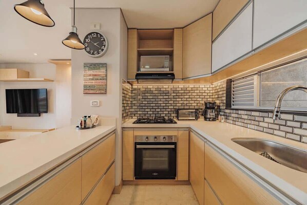 A compact kitchen with a microwave, stove, oven, and sink. - |EP| Medellin Top Floor Apt w/Pool, Views and Desk (Medellín)