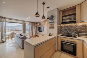 Eine moderne Küche mit Kochinsel, integriertem Backofen und Mikrowelle. Ein großes Fenster bietet Blick auf die Stadt.