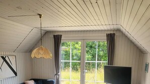 Una sala de estar acogedora con un sofá azul, una mesa de centro redonda y un televisor.