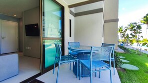 A modern outdoor seating area with a glass door leading to a pool, surrounded by greenery. - Itah Residence - Condomínio Beira-Mar (Ipojuca)