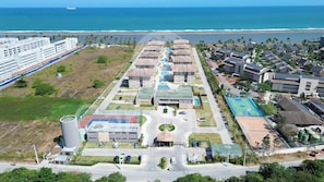 An aerial view of a resort with multiple buildings, a swimming pool, and a tennis court. - Itah Residence - Condomínio Beira-Mar (Ipojuca)