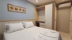 Quarto de hotel com cama, guarda-roupa e quadro na parede.
