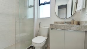 A bathroom with a glass shower enclosure, a toilet, and a sink with a mirror above it. - Itah Residence - Condomínio Beira-Mar (Ipojuca)