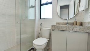 Une salle de bain avec une douche à parois de verre, des toilettes et un lavabo avec un miroir au-dessus.