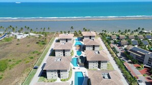Un complexe hôtelier comprenant plusieurs bâtiments, une piscine centrale et offrant une vue sur la plage.