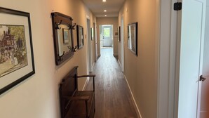 A hallway with wooden flooring, framed pictures on the walls, and a bench. - 3Bed3.5Bath @ Burk’s Falls's View (Burk's Falls)