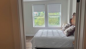 A bedroom with a large bed, two windows, and a view of greenery outside. - 3Bed3.5Bath @ Burk’s Falls's View (Burk's Falls)