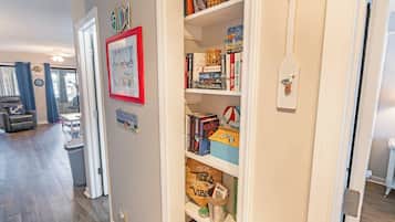 A hallway with a bookshelf, a framed picture, and a trash can.