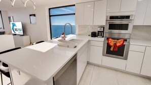 A modern kitchen with white cabinetry, a large window with a view, and a countertop with a coffee maker.