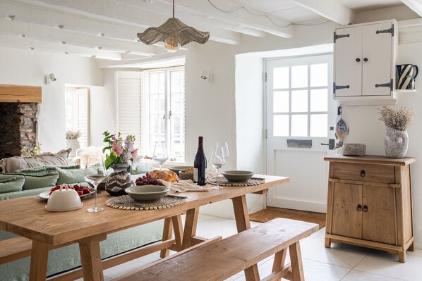 A wooden dining table set with food and wine, a bench, and a rustic cabinet.