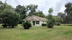 A single-story house with a front yard, surrounded by trees and a grassy lawn. - Karen’s Cove
Charming 2-bedroom house in terrific Darien with WiFi, AC (Darien)